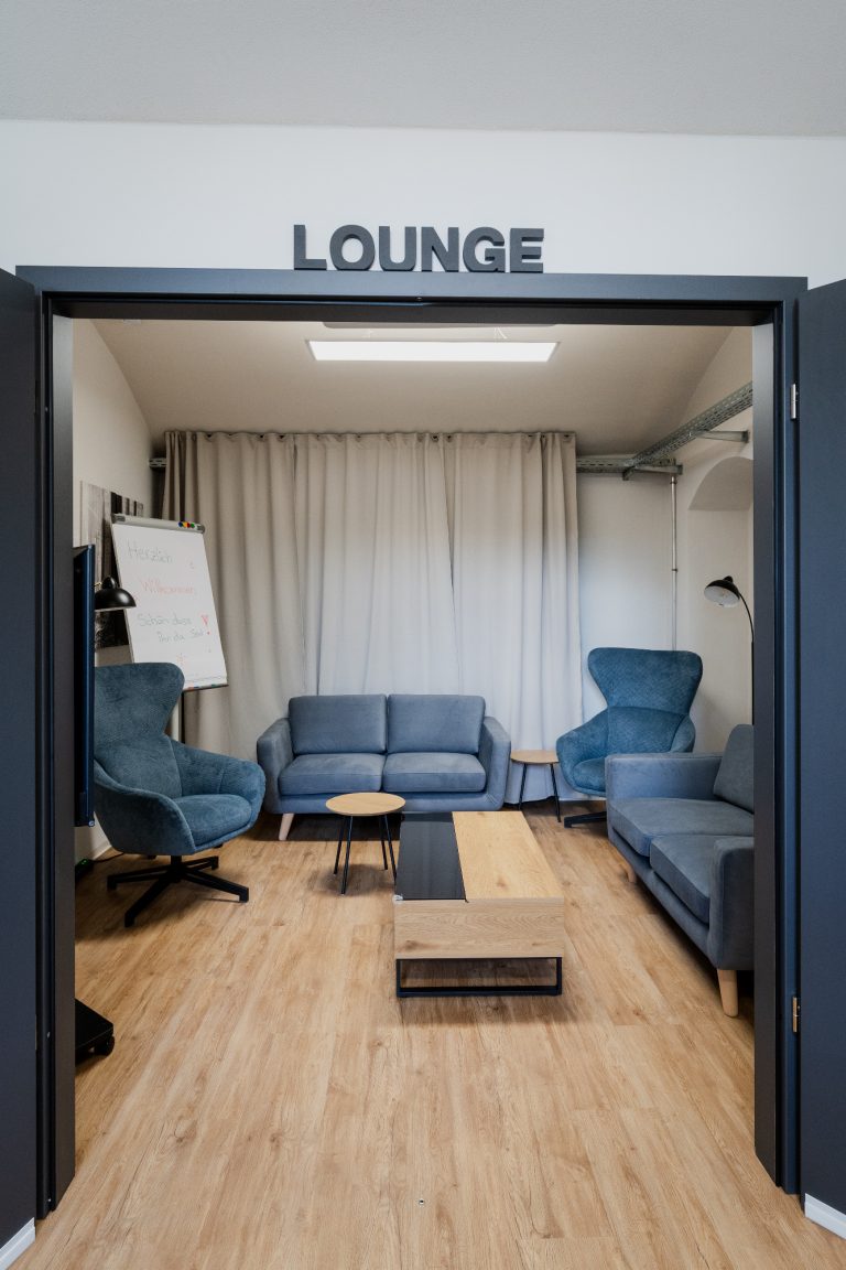 Meetingraum und Lounge Moderne Lounge mit blauen Sofas, Tisch und Vorhängen in hellen Farben.