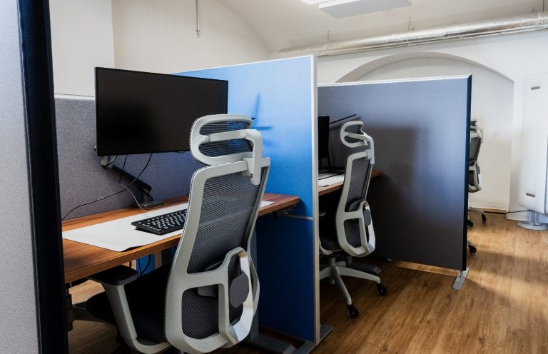 Modernes Büro mit mehreren Arbeitsplätzen, Hochtischen, Pflanzen und hellen Holzböden.
