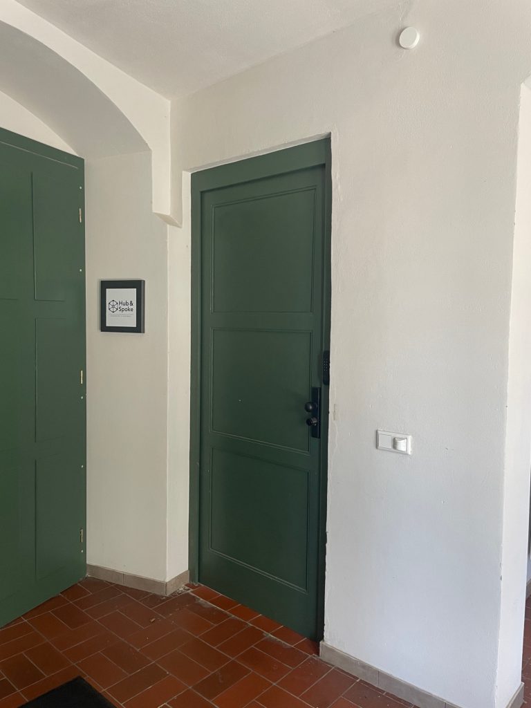 Eingang zum Coworking Space in Radebeul bei Dresden Grüne Tür in einem Flur mit weißen Wänden und Kachelsockel.