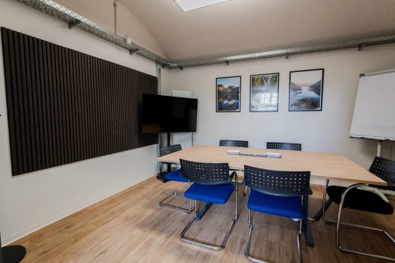 Moderne Besprechungsraum mit Tisch, Stühlen, Fernseher und Flipchart.