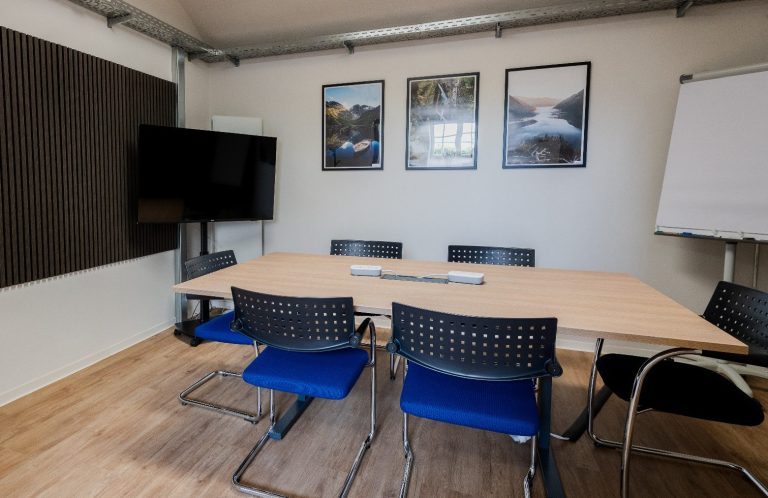Leerer moderner Konferenzraum mit einem Tisch, Stühlen, Fernseher und Flipchart.