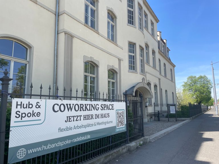 Außenansicht von der Meißner Straße Gebäude mit Schild für Coworking-Spaces, blauem Himmel und Bäumen im Hintergrund.
