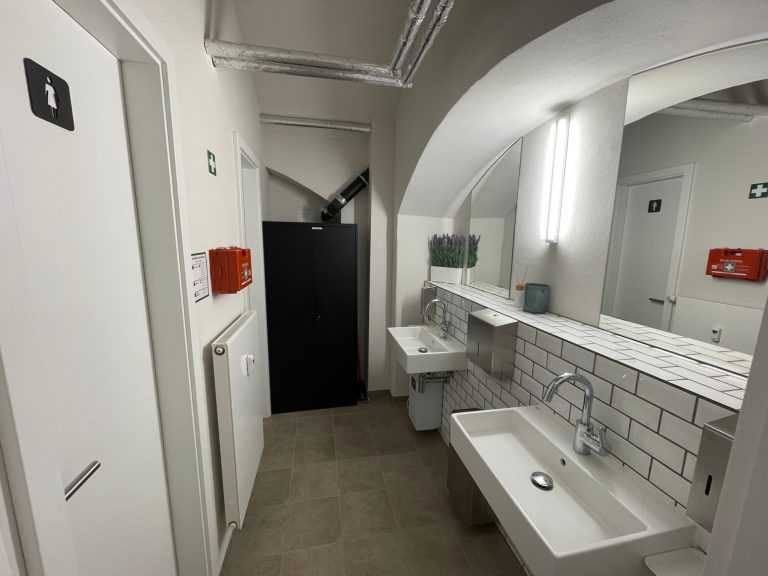 Bad Blick auf ein modernes Badezimmer mit Waschbecken und Toiletten in einem hellen Flur.