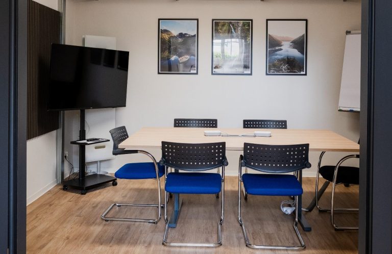 Meetingraum Leerer moderner Konferenzraum mit einem Tisch, Stühlen, Fernseher und Flipchart.